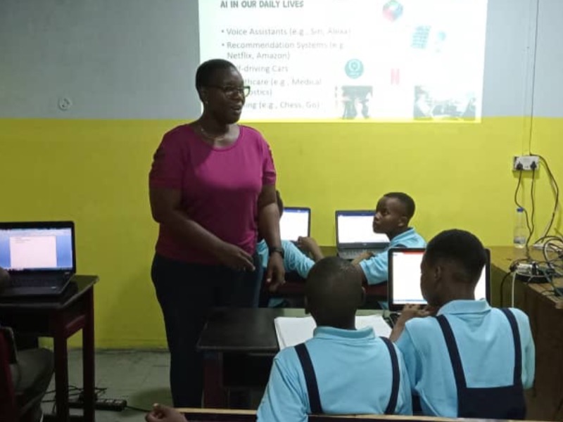 A classroom lesson on artificial intelligence, with students at laptops and slides projected