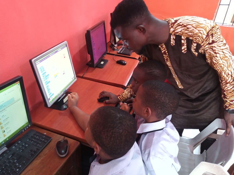 An instructor guiding students individually through an exercise at desktop computers